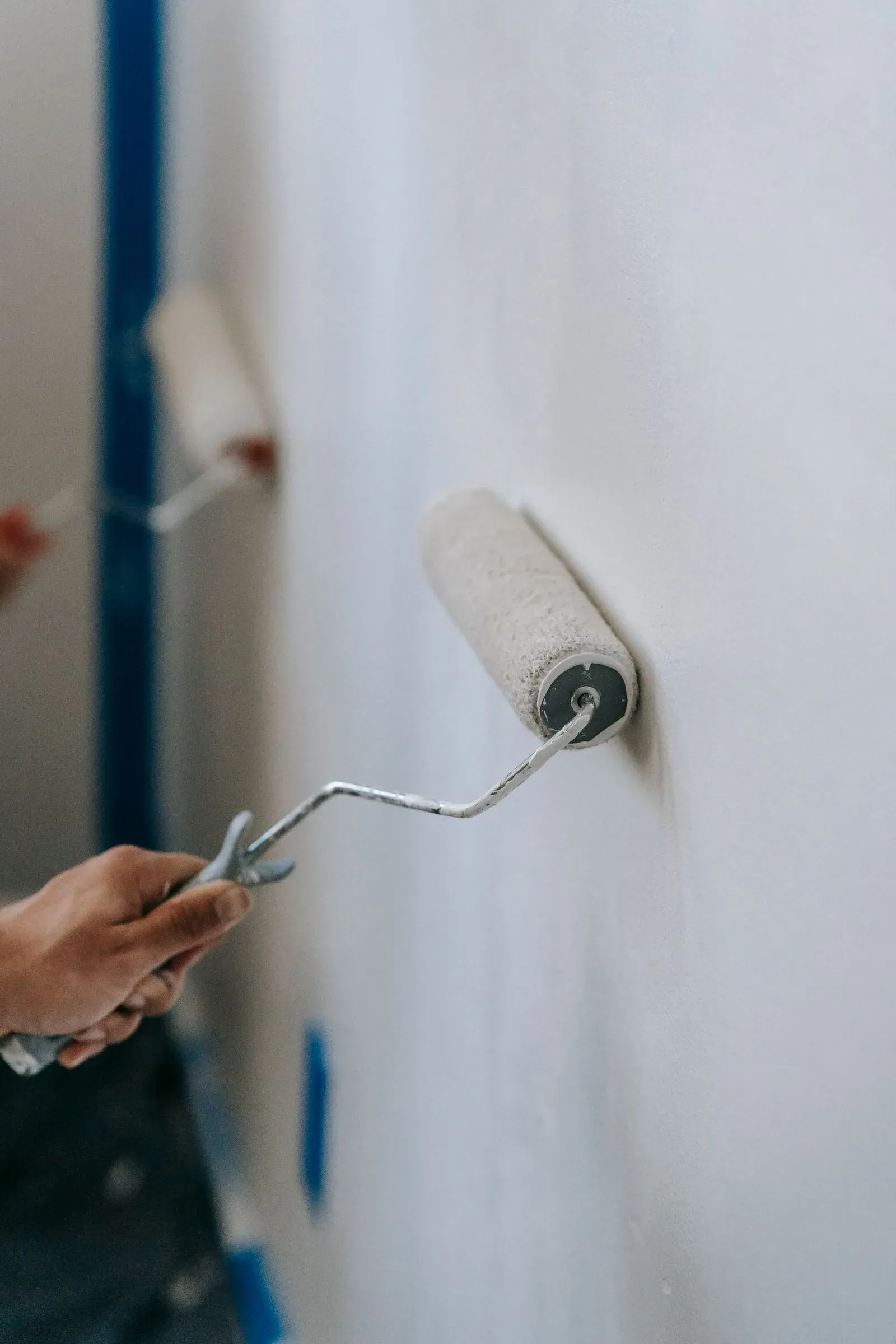 Paint roller applying white paint on a wall