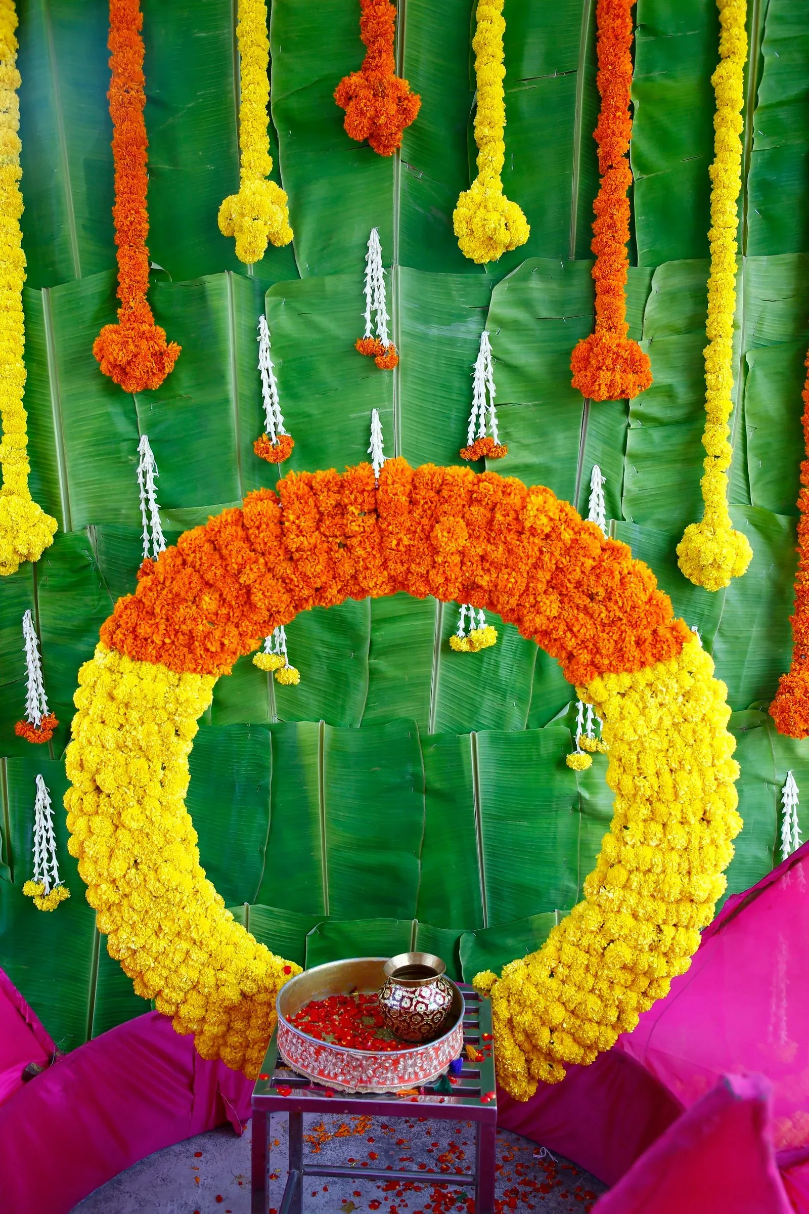 Marigold flower arch on green banana leaves