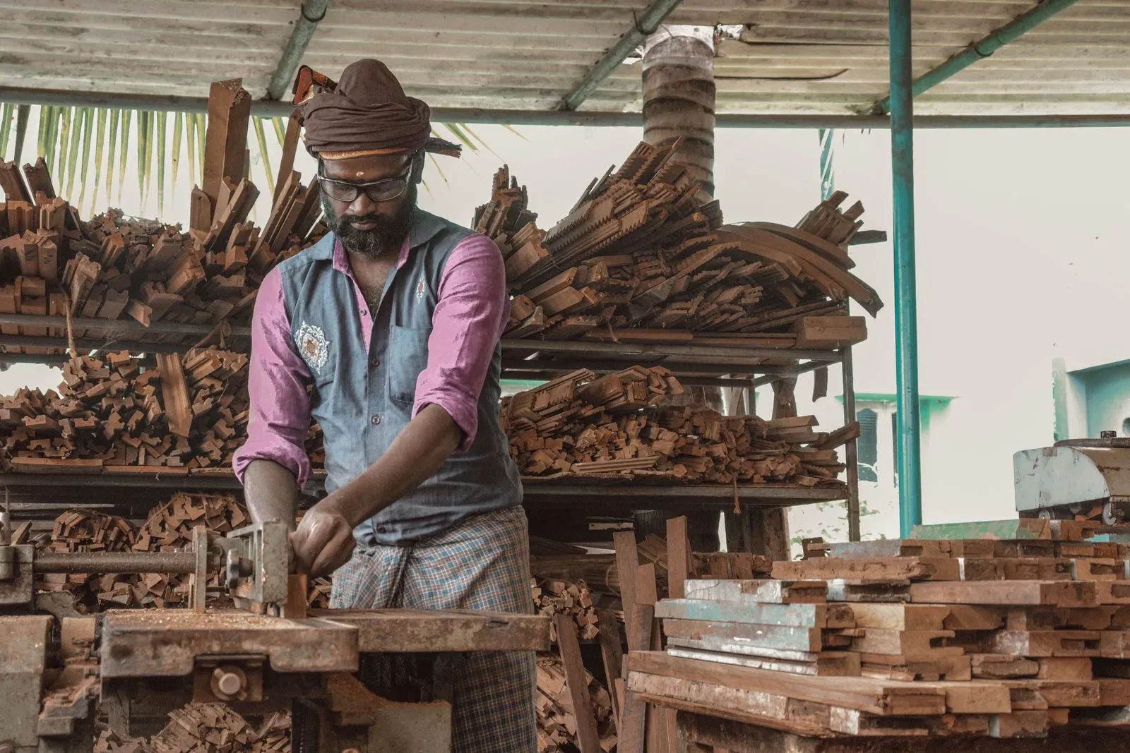 Carpenter shaping wood in a workshop full of timber
